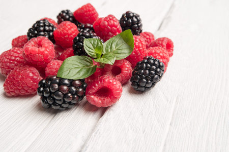 Ripe sweet raspberries and blackberries on wood table background