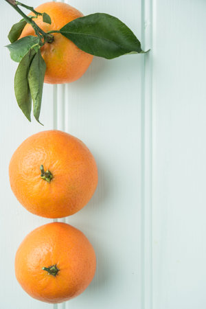Fresh clementines on wooden board with leaves. Top view with copy space.