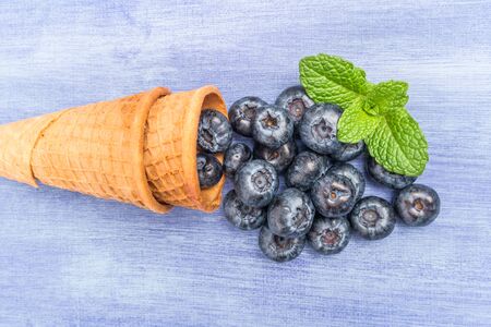 Waffle cones with blueberries and mint leaf on rustic textured background. Top view with copy space.の写真素材