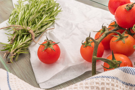 Organic cherry tomatoes with rosemary on wrinkled paperの写真素材