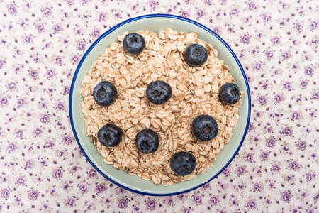 Oat flakes with blueberries in a bowl on cute fabric background. Top view with copy space.の写真素材