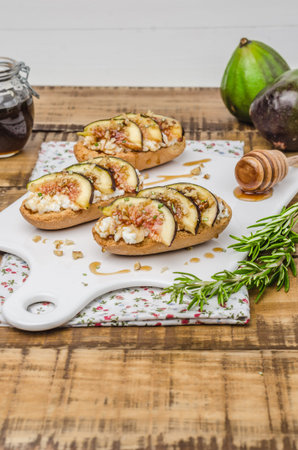 Swedish toasts with figs, cheese, rosemary, honey and walnuts on a cutting board