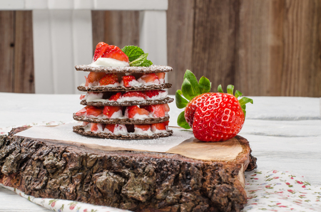 Chocolate belgian waffles with strawberries, whipped cream and mint leaf on wooden tableの写真素材