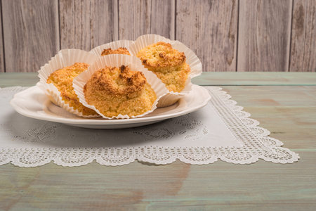 Close up of homemade coconut macaroons, cookie recipe in the oven on rustic wooden background. Top...