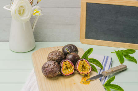 Passion fruits with leaves, knife and white flowers in jar on the vintage wooden table.の写真素材