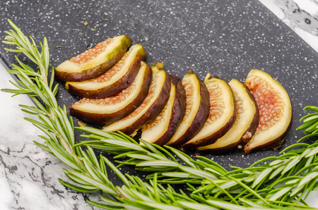Fresh sliced figs and rosemary on cutting boardの写真素材