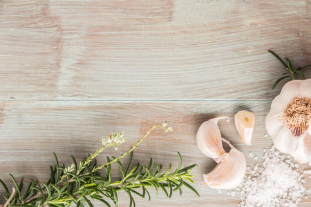 Bunch of fresh of garden rosemary on wooden table, rustic style, fresh organic herbs with salt and garlic. Top view with copy spaceの写真素材