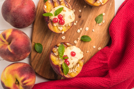 Grilled peaches with yogurt, gooseberries and mint leaves on wooden tableの写真素材