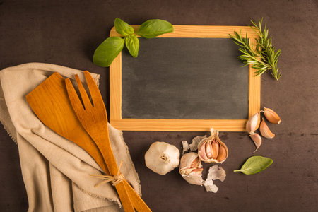 Blackboard for your text, fresh garden herbs on stone table. Basil, garlic and rosemary. Cooking ingredients. Top view with copy spaceの写真素材