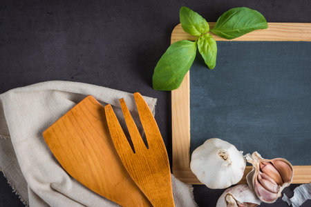 Blackboard for your text, fresh garden herbs on stone table. Basil and garlic. Cooking ingredients....