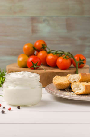 Organic cherry tomatoes with rosemary, swedish toasts and cream cheese on rustic wooden tableの写真素材