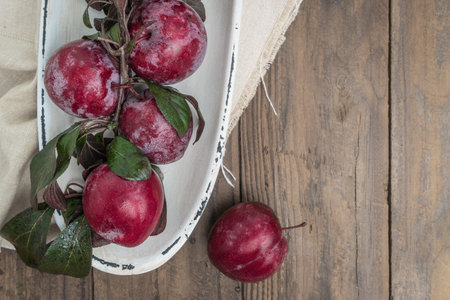 Branch of delicious red plums on a wooden background