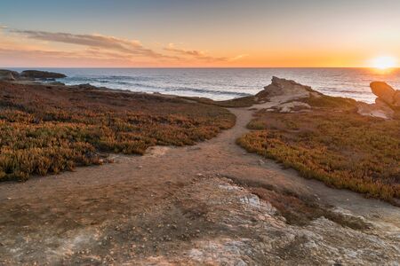 Sunset on the beach with rocks in Porto Covo in Alentejo, Portugal.の写真素材
