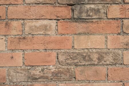 Old brick wall with cracks and scratches. Brick wall background. Distressed wall with broken bricks texture. House facadeの写真素材