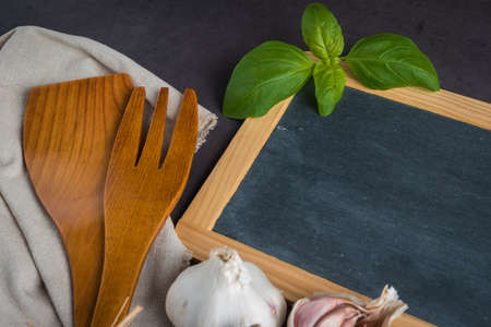 Blackboard for your text, fresh garden herbs on stone table. Basil and garlic. Cooking ingredients. Top view with copy spaceの写真素材