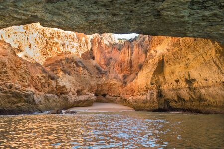 Scenic golden cliffs near Benagil, Lagoa. This beach is a part of famous tourist region Algarve. View from a boat on the ocean.の写真素材