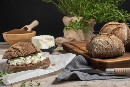 Homemade farm bread with cottage cheese curd and thyme herb, malt flour and curd cream in bowl on...