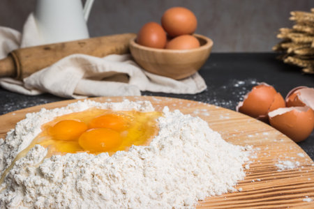 Eggs, dough, flour and rolling-pin on wooden table background. Preparation for making homemade...