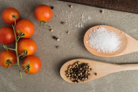 Top view of a bunch of natural cherry tomatoes, salt and pepper on cement background with copy spaceの写真素材