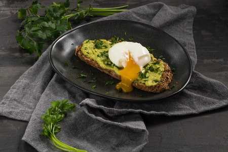 Avocado sandwich with poached egg. Avocado and egg on toasted bread for healthy breakfast or snack, copy space.の写真素材