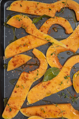 Roasted sliced butternut squash seasoned with salt, sweet pepper, pepper and thyme on baked dish. Top viewの写真素材