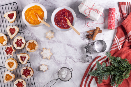 Flat lay with christmas cookies on marble surface with christmas decorative pine branch, jam, gift and cookie cuttersの写真素材