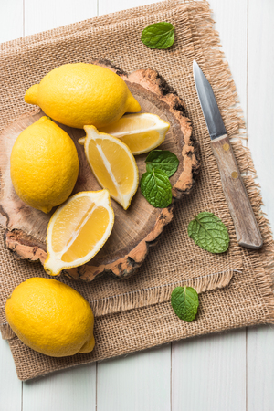 Slices, half fresh juicy lemon with mint leaves and knife on the vintage wooden table. Top view with copy space.の写真素材