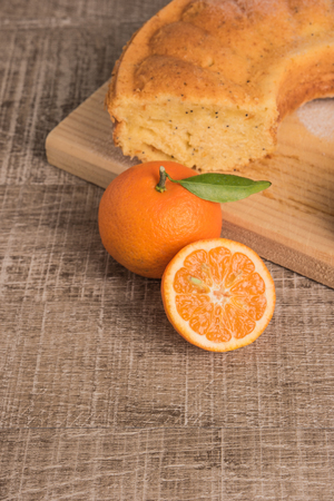 Slices of clementine cake with powdered sugar topping. Cake on a board with fresh clementines on wooden board.の写真素材