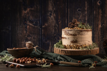 Delicious naked chocolate and hazelnuts cake on table rustic wood kitchen countertop.