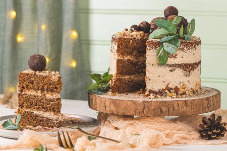 Slice of delicious naked chocolate and hazelnuts cake on table rustic wood kitchen countertop.の写真素材
