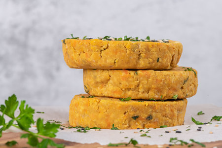 Raw veggie burger with chickpeas, vegetables and parsley leaves on kitchen countertop