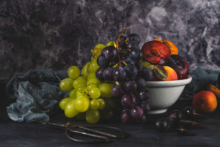 Freshly washed fruits with water droplets. bright high key look conveys freshness. Variety of fresh grapes, apricot and plumes on dark background. Fruit sources of vitaminsの写真素材