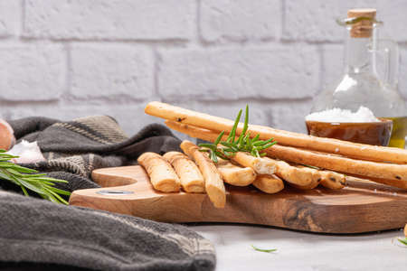 Traditional italian breadsticks grissini with rosemary, parmesan cheese, olive oil, garlic and salt on a gray background.の写真素材