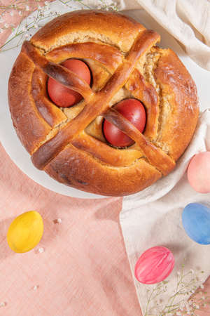 Portuguese traditional Easter cake. Folar with eggs on easter table. Blossom flowers and colorful painted eggsの写真素材