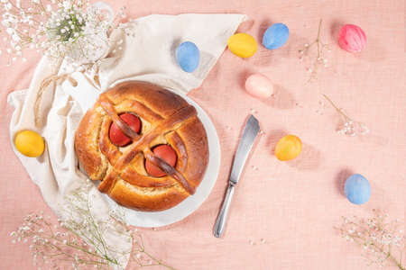 Portuguese traditional Easter cake. Folar with eggs on easter table. Blossom flowers and colorful painted eggsの写真素材