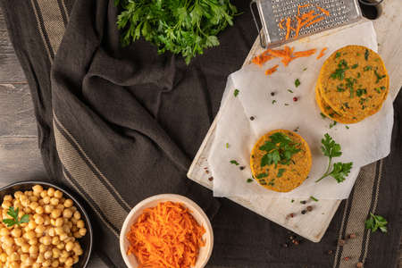 Raw veggie burger with chickpeas, vegetables and parsley leaves on kitchen countertopの写真素材