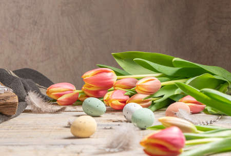 Easter eggs and blossom tulips on background. Top view flat lay.Bright pink and yellow tulip spring flower . Easter composition with colorful Easter eggs and spring flowers tulips on wooden backgroundの写真素材