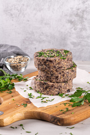 Raw veggie burger with black beans on wood countertop