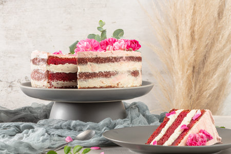 Red velvet naked cake with fresh roses and swiss buttercream on kitchen countertop