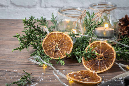 Background for christmas with burning candles and natural decoration on rustic wooden board. Background with pine branches and space for your text.の写真素材
