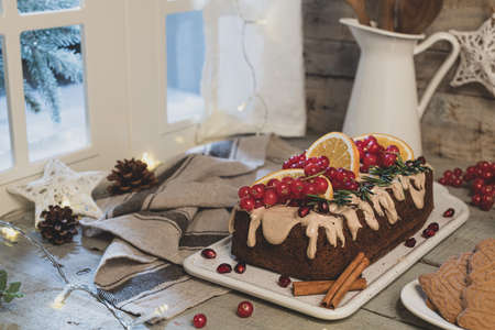 Traditional christmas cinnamon cake decorated with fruits and spekulatius cookies cream on a kitchen countertop.の写真素材