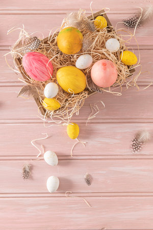 Easter pink, yellow and white eggs in wooden box and white tulips