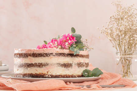 Chocolate naked cake with fresh roses and swiss buttercream on a white backgroundの写真素材