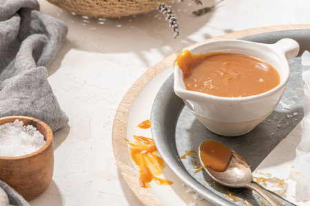 Homemade salted caramel in a ceramic bowl. Delicious sauce with sea salt for ice cream and dessertsの写真素材