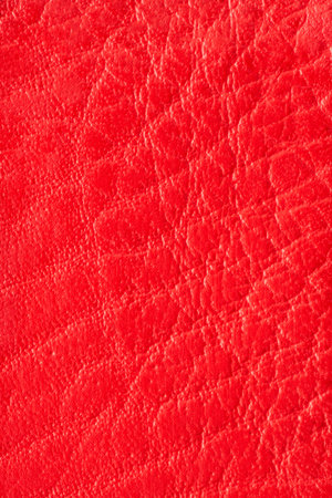 Red artificial or synthetic leather background with neat texture and copy space, colorful fabric sample with leather-like finish aimed for upholstery, fashion, sewing or footwear projectsの写真素材