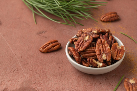 Pecan nuts in ceramic bowl on kitchen background with copy space for text