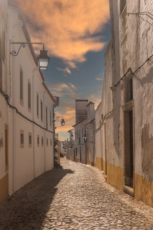 The view of narrow paved street of Evora with the cozy white and yellow houses. Evora. Alentejo. Portugalの写真素材