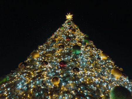 A towering Christmas tree, adorned with twinkling lights and colorful ornaments, creates a festive and magical atmosphere.の写真素材