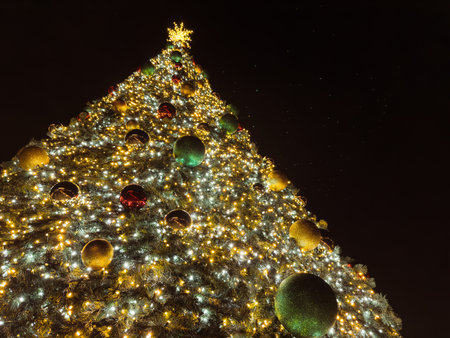 A towering Christmas tree, adorned with twinkling lights and colorful ornaments, creates a festive and magical atmosphere.の写真素材