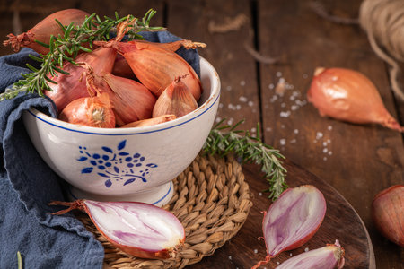 A rustic kitchen with shallots in a bowl on a wooden cutting board, creating a cozy, homely atmosphereの写真素材